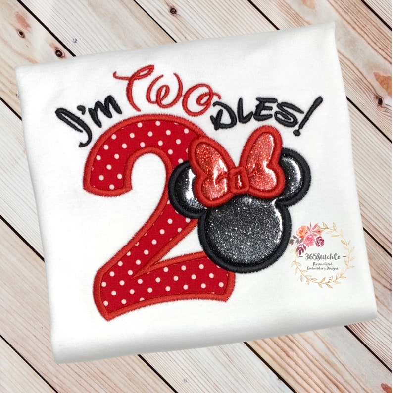 May include: White t-shirt with red and black embroidered design. The design features the number "2" with red polka dots, the words "I'm Two-dles!" and a black and silver Minnie Mouse head with a red bow.
