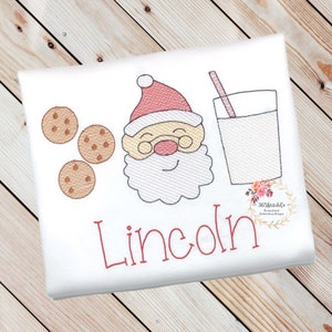 May include: Embroidered design of Santa Claus with a glass of milk and cookies, with the name "Lincoln" stitched below.