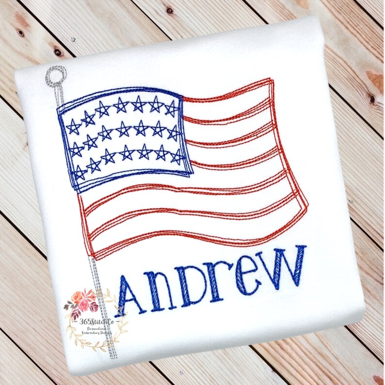 K&ouml;nnte beinhalten: Gestickte Darstellung einer amerikanischen Flagge mit dem Namen Andrew darunter. Die Flagge ist rot, wei&szlig; und blau und weht im Wind.