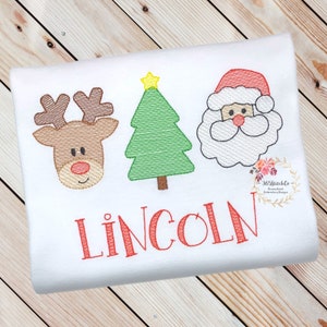 May include: Embroidered Christmas design featuring a reindeer, a Christmas tree, and Santa Claus. The design is in red, green, brown, and white. The name "LINCOLN" is embroidered below the design.