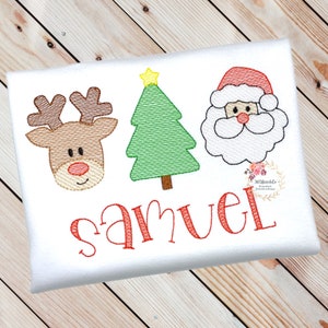 May include: A white onesie with a red embroidered reindeer, Christmas tree, and Santa Claus. The name "Samuel" is embroidered in red below the images.
