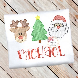 May include: A white onesie with a red reindeer, green Christmas tree, and Santa Claus face embroidered on it. The name "Michael" is embroidered in red below the images.