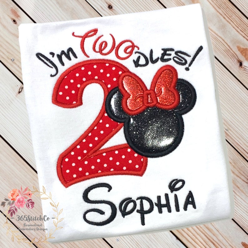 May include: White t-shirt with red and black embroidery. The embroidery includes the number 2 with red polka dots, a black and red Minnie Mouse head, and the text "I'm Two-dles!" and "Sophia".