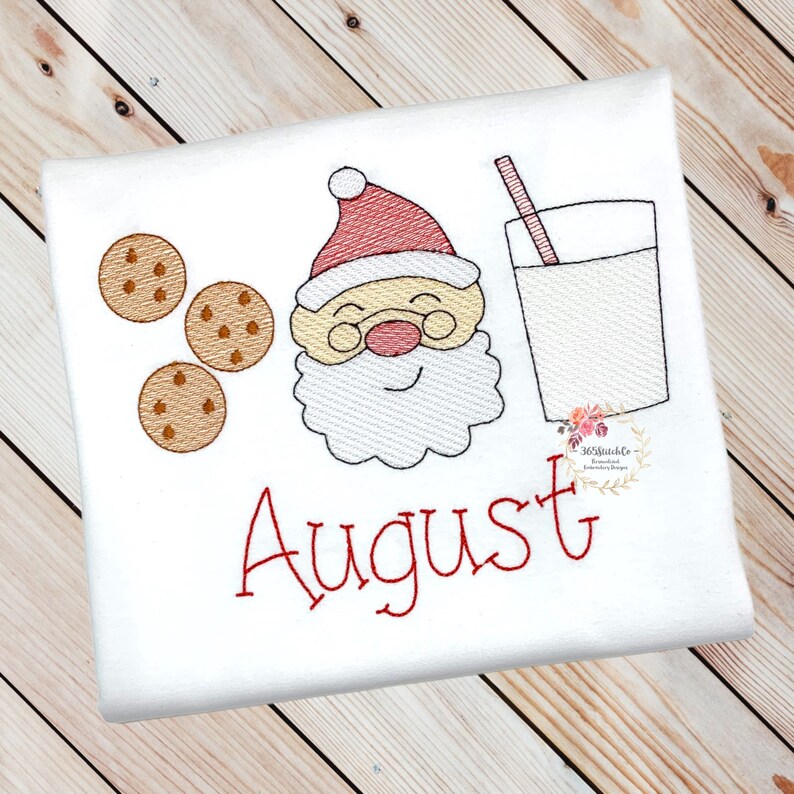 May include: Embroidered design featuring a cartoon Santa Claus with a glass of milk and cookies. The name "August" is stitched in red below the design.