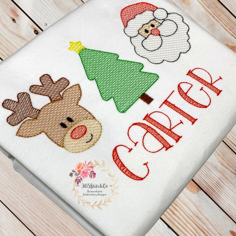 May include: Embroidered Christmas design featuring a red-nosed reindeer, a green Christmas tree, and Santa Claus. The design is personalised with the name "Carter" in red thread.