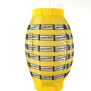 May include: A yellow and black woven pendant light fixture hangs from a white ceiling.