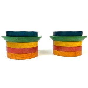 Peut inclure: Deux anneaux d'empilage en bois dans un arc-en-ciel de couleurs, y compris le bleu, le vert, le jaune, le rouge et l'orange. Les anneaux sont empilés les uns sur les autres, créant une tour colorée.