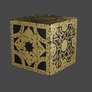 May include: A black cube with a gold intricate design. The cube has a geometric pattern on each side.