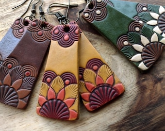 May include: Three pairs of leather earrings with intricate floral designs. The earrings are in shades of brown, green, and yellow with red and white accents.