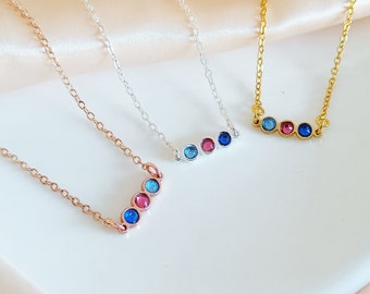 Puede incluir: Tres delicados collares con pequeñas piedras preciosas de colores. Los collares son de plata, oro y oro rosa. Cada collar tiene tres piedras preciosas: azul, rosa y azul.