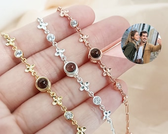 Puede incluir: Tres pulseras de plata con un diseño de flores y una pequeña piedra redonda en el centro. Las pulseras son de oro, plata y oro rosa.