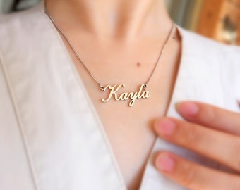 May include: A silver necklace with a cursive nameplate pendant that reads "Kayla".