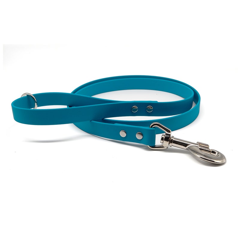 Puede incluir: Una correa para perro de color azul cerceta brillante con un dise&ntilde;o de cinta plana y lisa, equipada con herrajes de metal plateado, incluyendo un mosquet&oacute;n giratorio resistente en un extremo y una anilla cerca del asa, fijada con remaches.