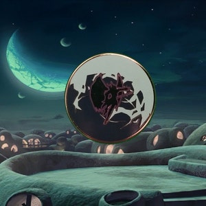May include: A round, silver pin with a black silhouette of a creature with wings against a white background. The pin is set against a backdrop of a night sky with a crescent moon and stars.