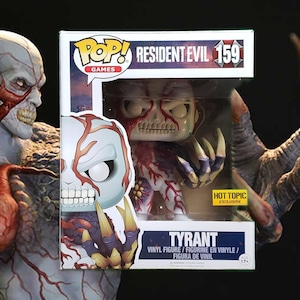 May include: A Pop! Games vinyl figure of the Tyrant from Resident Evil. The figure is a Hot Topic exclusive and is numbered 159. The figure is white with red and black details. The figure is holding a large, clawed hand.