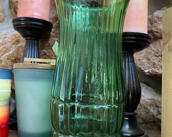 May include: A green glass vase with a ribbed design. The vase is tall and slender with a wide mouth.