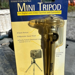 May include: A gold-coloured mini tripod for digital and 35mm cameras and camcorders. The tripod extends to 6 1/2 inches and has a quick release, adjustable swivel head, and a convenient carrying strap.
