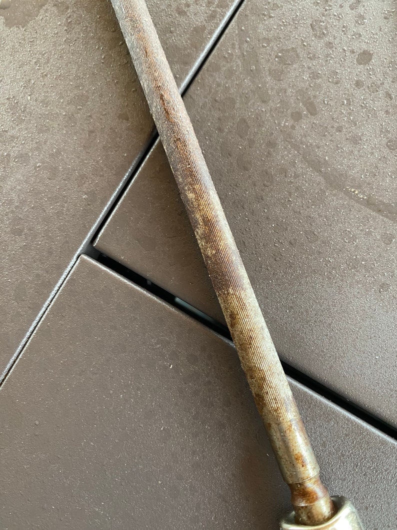 May include: A close-up of a metal file with a rough, textured surface. The file is rusty and has a brown patina. The file is lying on a brown surface.