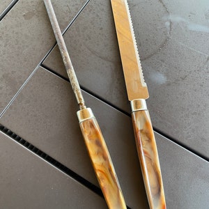 May include: A close-up of two kitchen tools: a brown and beige handled knife with a serrated blade and a brown and beige handled metal sharpening steel.