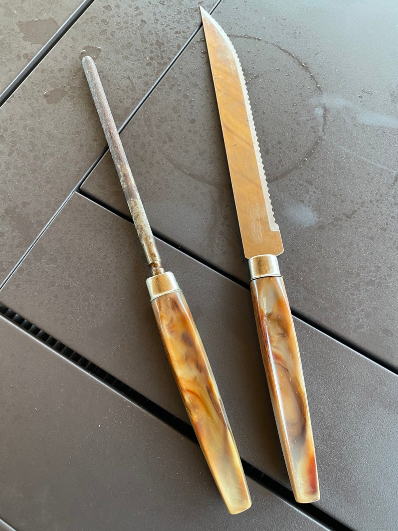 May include: A close-up of two kitchen tools: a brown and beige handled knife with a serrated blade and a brown and beige handled metal sharpening steel.