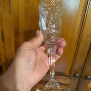 Puede incluir: Una flauta de champán de cristal tallado transparente con un diseño de diamantes y abanicos. El tallo presenta una cuenta facetada decorativa. La copa tiene una base ancha y un cuenco delgado y alargado.