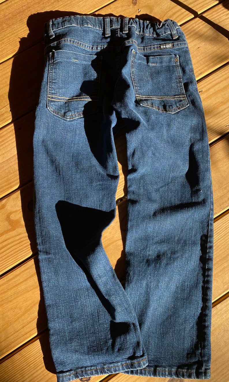 Op de afbeelding: Een donkerblauwe spijkerbroek met lichtbruine stiksels rond de zakken en naden. De broek heeft een ontspannen pasvorm en een rechte pijp.