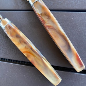 May include: Two brown and white patterned kitchen knives with silver handles.