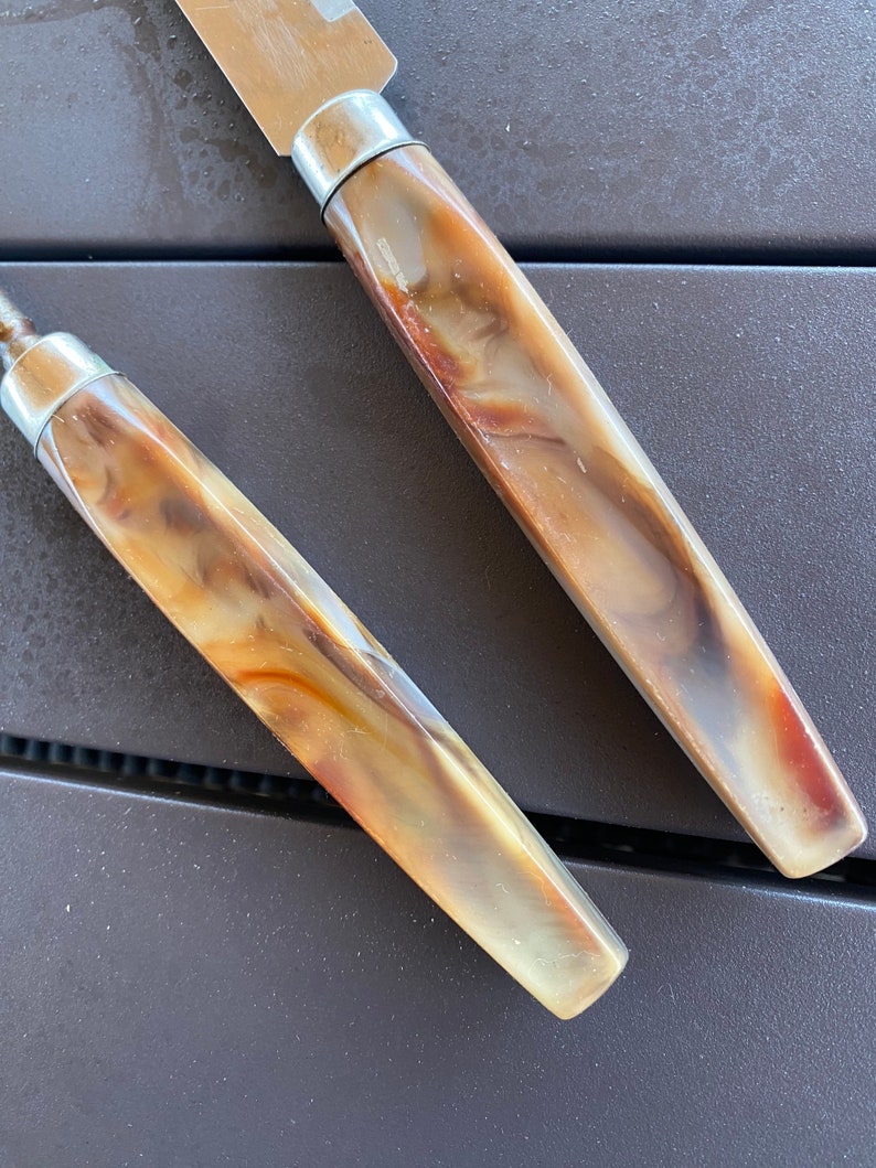 May include: Two brown and white patterned kitchen knives with silver handles.