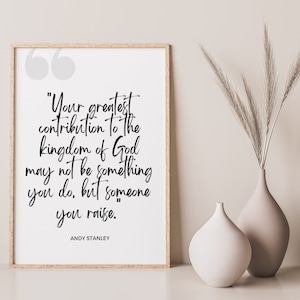 Può includere: Una stampa incorniciata con sfondo bianco e testo nero. La citazione recita "Il tuo più grande contributo al regno di Dio potrebbe non essere qualcosa che fai, ma qualcuno che allevi." La citazione è attribuita ad Andy Stanley.