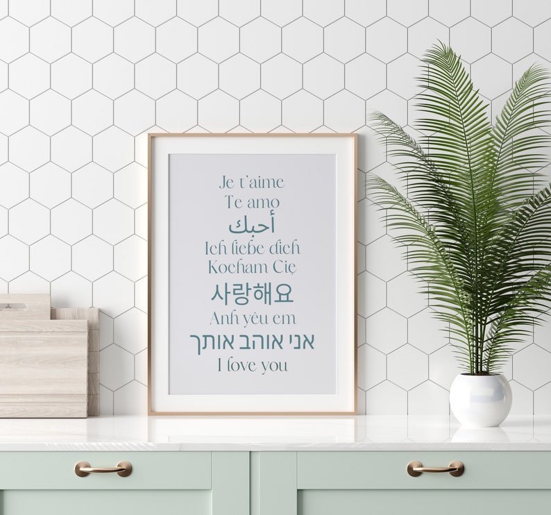 May include: A framed print with a white background and teal text. The text says "Je t'aime, Te amo, أحبك, Ich liebe dich, Kocham Cię, 사랑해요, Anh y&ecirc;u em, אני אוהב אותך, I love you".