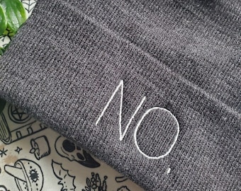 Könnte beinhalten: Eine graue Mütze mit dem Wort "NO." in weiß auf der Seite gestickt.