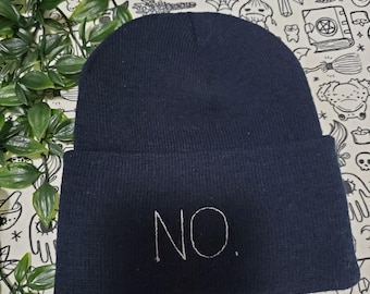 Könnte beinhalten: Schwarze Mütze mit weißer Stickerei, die "NO." lautet.