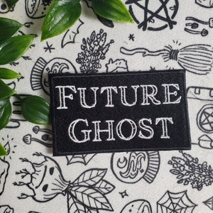 Op de afbeelding: Zwarte geborduurde patch met witte tekst die "FUTURE GHOST" luidt op een witte achtergrond met zwart-witte illustraties van verschillende occulte symbolen.