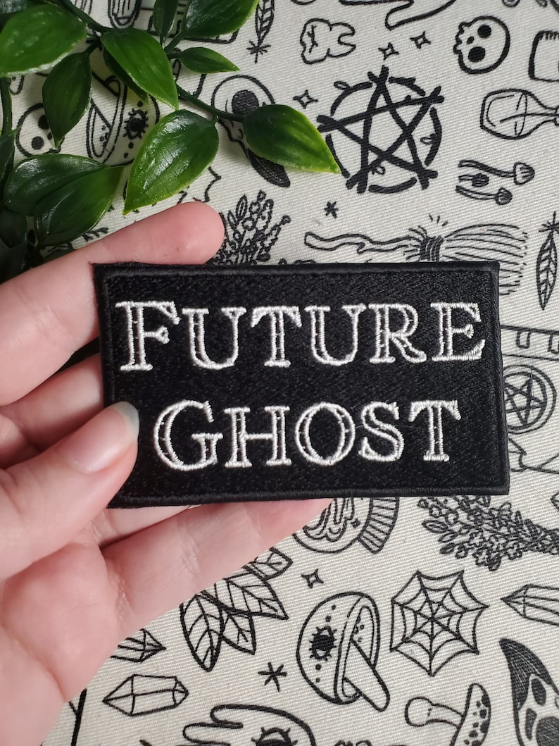 Op de afbeelding: Zwarte geborduurde patch met witte tekst die "FUTURE GHOST" luidt.