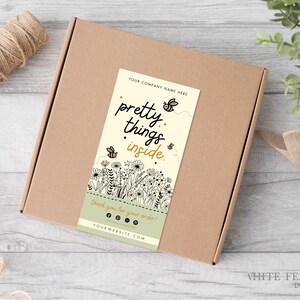 Può includere: Una scatola di cartone marrone con un'etichetta beige e verde che dice "pretty things inside." L'etichetta ha un disegno floreale con api e il testo "YOUR COMPANY NAME HERE" e "YOURWEBSITE.COM".