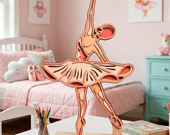 Puede incluir: Escultura de bailarina de madera en capas en tonos melocotón y naranja, en pose de baile. La escultura está montada sobre una base rectangular de madera. La bailarina lleva un tutú, con los brazos levantados. El fondo incluye un dormitorio infantil con decoración rosa.