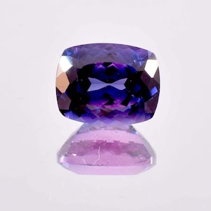 Può includere: Una pietra preziosa di colore viola scuro con taglio a cuscino. La pietra preziosa è sfaccettata e ha un'alta lucidatura.
