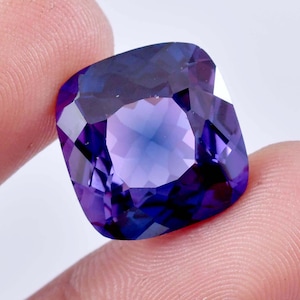 Può includere: Un grande ametista tagliato a cuscino, di colore viola intenso. La gemma ha un taglio sfaccettato e un alto grado di brillantezza.
