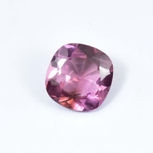 May include: A cushion-cut pink gemstone with a faceted surface.