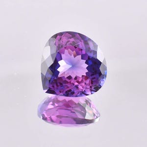 May include: A heart-shaped gemstone with a purple to blue color gradient. The gemstone is faceted and has a high polish.
