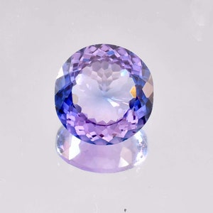 Può includere: Una pietra preziosa ovale sfaccettata di colore viola e blu.
