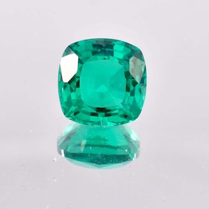Könnte beinhalten: Ein leuchtend grüner Smaragd mit einem Kissen-Schliff. Der Edelstein reflektiert das Licht und zeigt seine Brillanz.