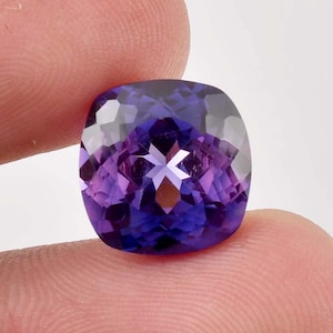 以下が含まれることがあります： 紫色から青みがかった紫色の大きなクッションカットのファセットアメジストの宝石です。