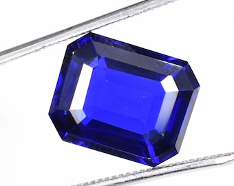 Può includere: Una gemma blu scuro con taglio rettangolare smeraldo, tenuta in una pinza.