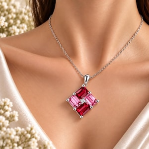 Puede incluir: Un collar de plata con un colgante cuadrado compuesto por cuatro piedras preciosas de corte baguette dispuestas en forma de molinete. El colgante incluye dos piedras de color rojo intenso y dos de color rosa claro, con una piedra clara en el centro.