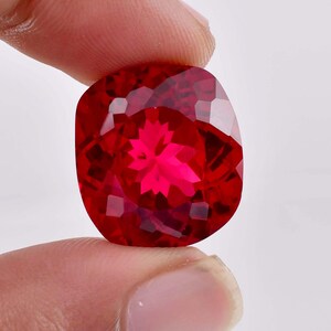 May include: A deep red gemstone with a star-shaped cut. The gemstone is faceted and has a high polish.