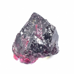 May include: A rough, dark purple and black gemstone with a shiny, crystalline surface.