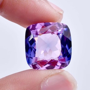 Può includere: Una grande gemma a cuscino con un gradiente di colore viola e blu. La gemma è sfaccettata e ha un'alta lucidatura.