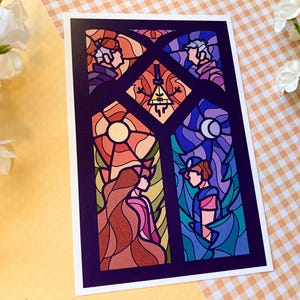 May include: A colorful stained-glass style art print featuring characters and symbols from a popular animated series. The artwork showcases a vibrant palette of reds, oranges, blues, and purples, with a dark purple border. The design is reminiscent of a church window.