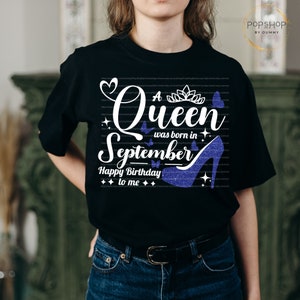 May include: Black t-shirt with white text that reads "A Queen was born in September Happy Birthday to me". The text is surrounded by glitter and butterflies. A blue glitter high heel shoe is also on the shirt.